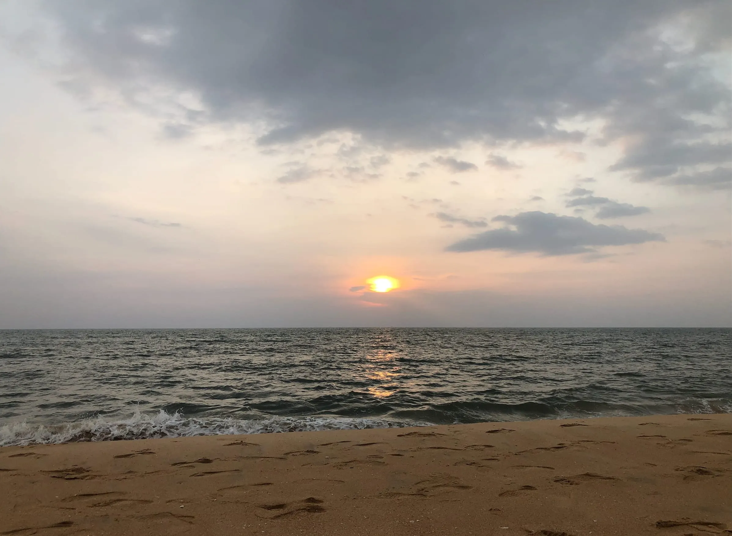 Ezhara Beach, Kannur: the sun low over the Arabian Sea, with footprints in the sand