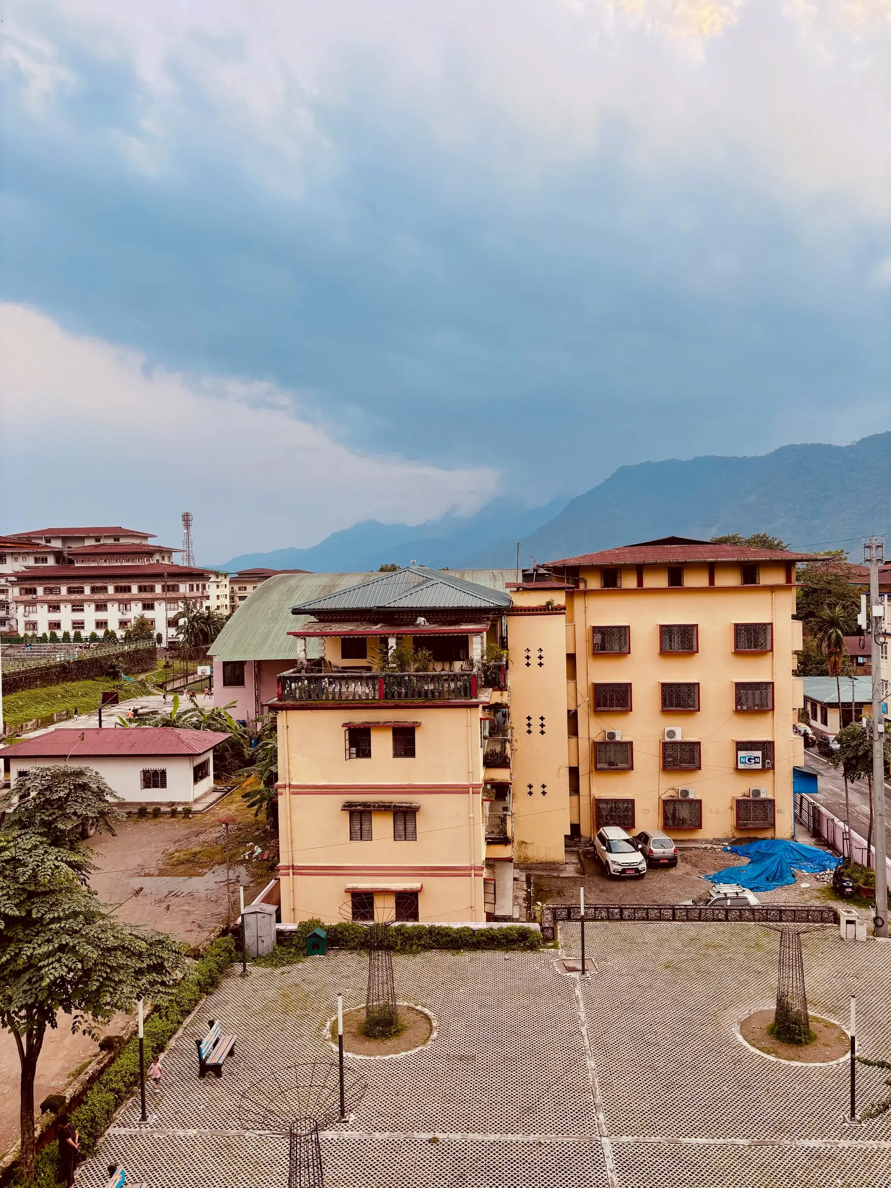 Phuentsholing from above: yellow and white buildings and the first green hills of Bhutan under rain clouds