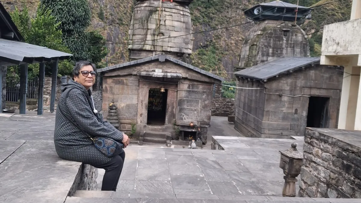Jhumka in the stone courtyard of Yogdhyan Badri at Pandukeshwar, two stone temples beneath a cliff