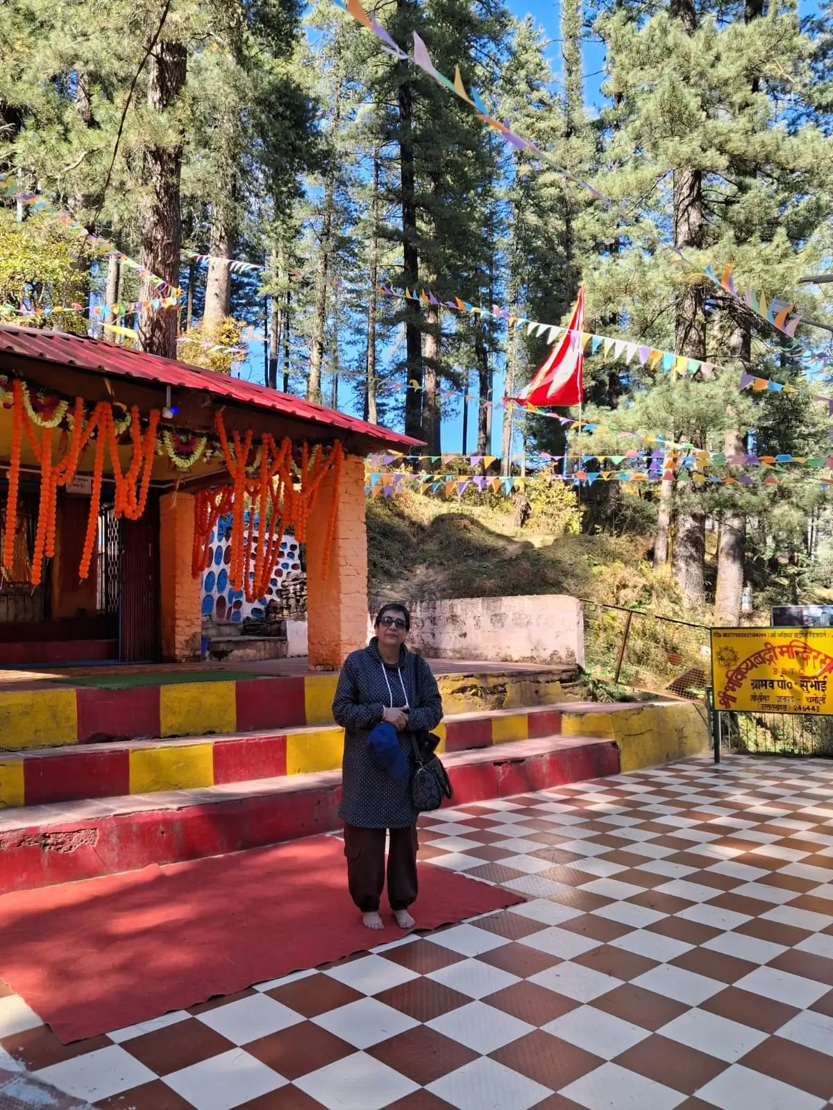 Jhumka at Bhavishya Badri in Subhain, the shrine hung with marigolds, pines and prayer flags behind
